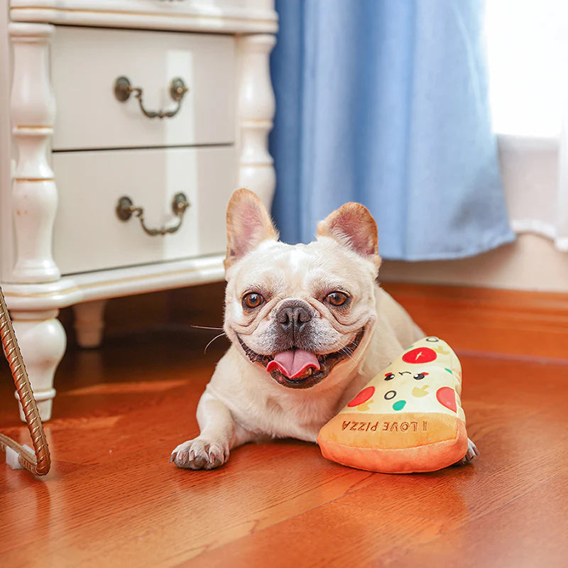 Smiling french bulldog lying on a wooden floor with the pizza-shaped hugsmart dog plush toy
