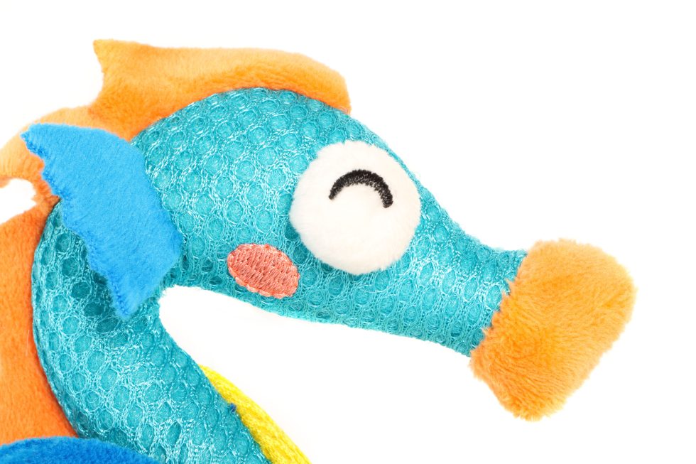 Plush seahorse toy with orange fins and blue body on a white background