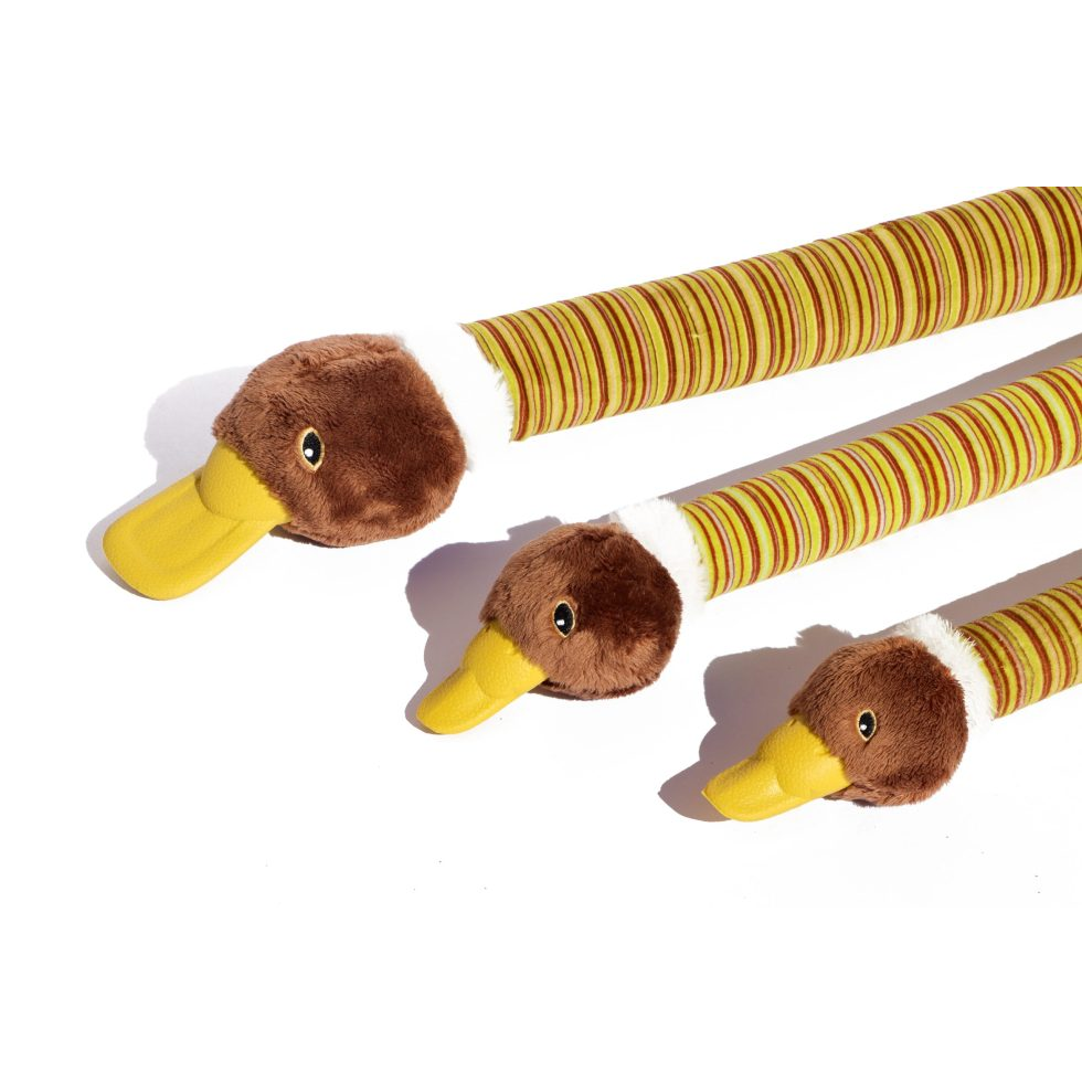 Three GiGwi plush dog toys sitting parallel to each other which are shaped like a duck with a long stripy neck and green body, looking up at the camera whilst on a white background