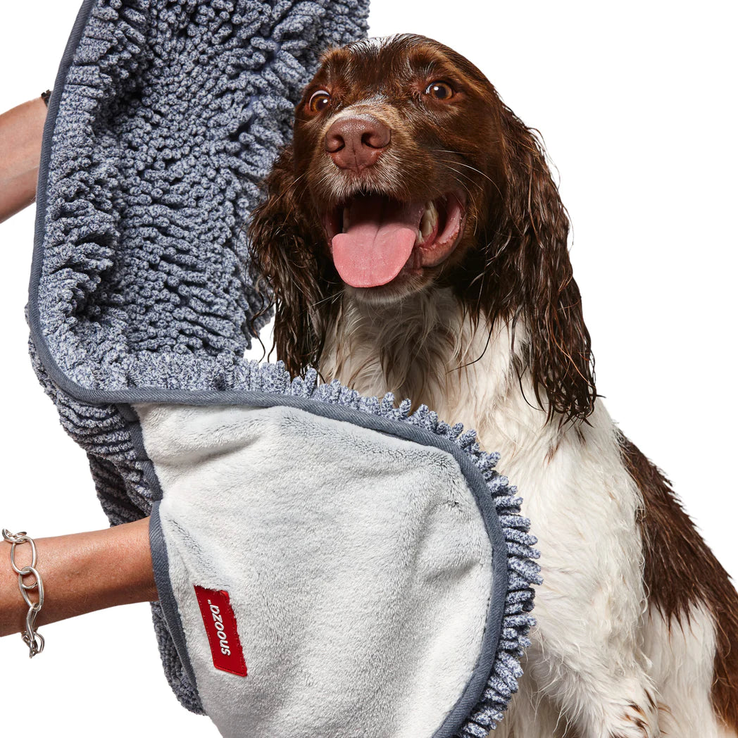 Smiling Dog being dried with a grey Snooza microfiber towel by a person on a white background