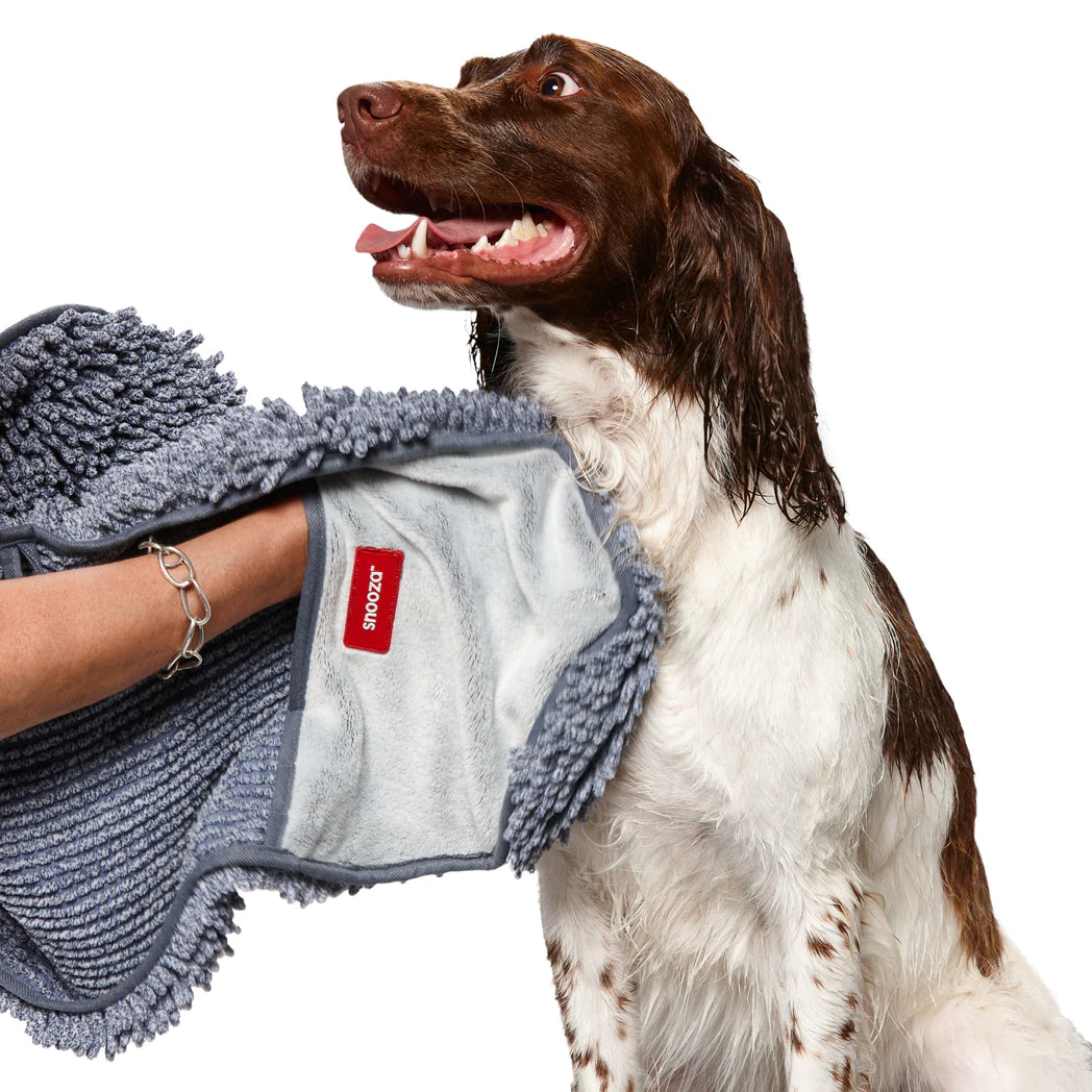 Smiling Dog being dried with a grey Snooza microfiber towel by a person on a white background